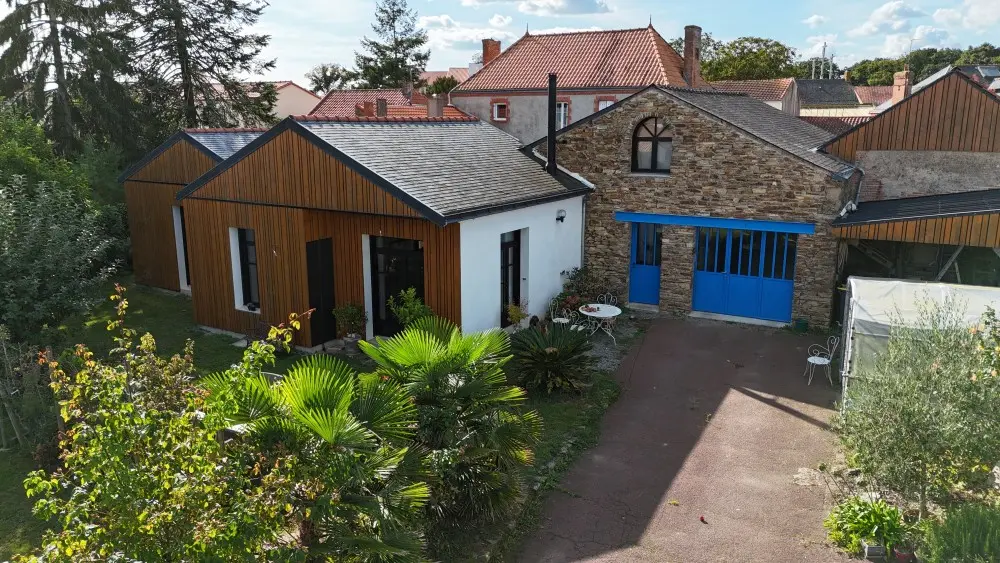 Vue d'ensemble du bâtiment ancien rénové avec son extension en bardage bois